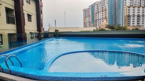 Une piscine avec un bord carrelé et un escalier en métal.