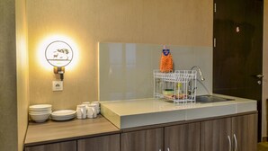 Une cuisine avec un plan de travail blanc, une serpillière orange suspendue et un évier.