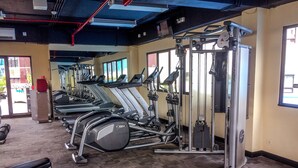 Une salle de sport équipée de tapis de course, d’appareils de musculation et d’un banc.