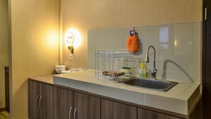 Une cuisine compacte comprenant un évier, un égouttoir et un porte-serviettes fixé au mur.