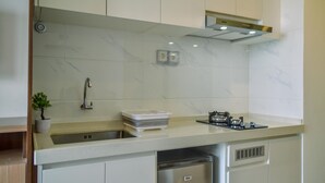 Een moderne keuken met witte kastjes, een roestvrijstalen spoelbak en een compacte vaatwasser.
