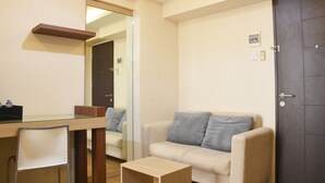 A modern living room with a glass dining table, a sofa, and a small wooden coffee table. - Comfort Living 2BR at Kebagusan City Apartment (Jakarta)
