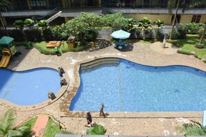 A swimming pool with a curved design, surrounded by a stone pathway and greenery. - Comfort Living 2BR at Kebagusan City Apartment (Jakarta)