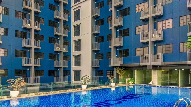 A swimming pool surrounded by a modern building with balconies.