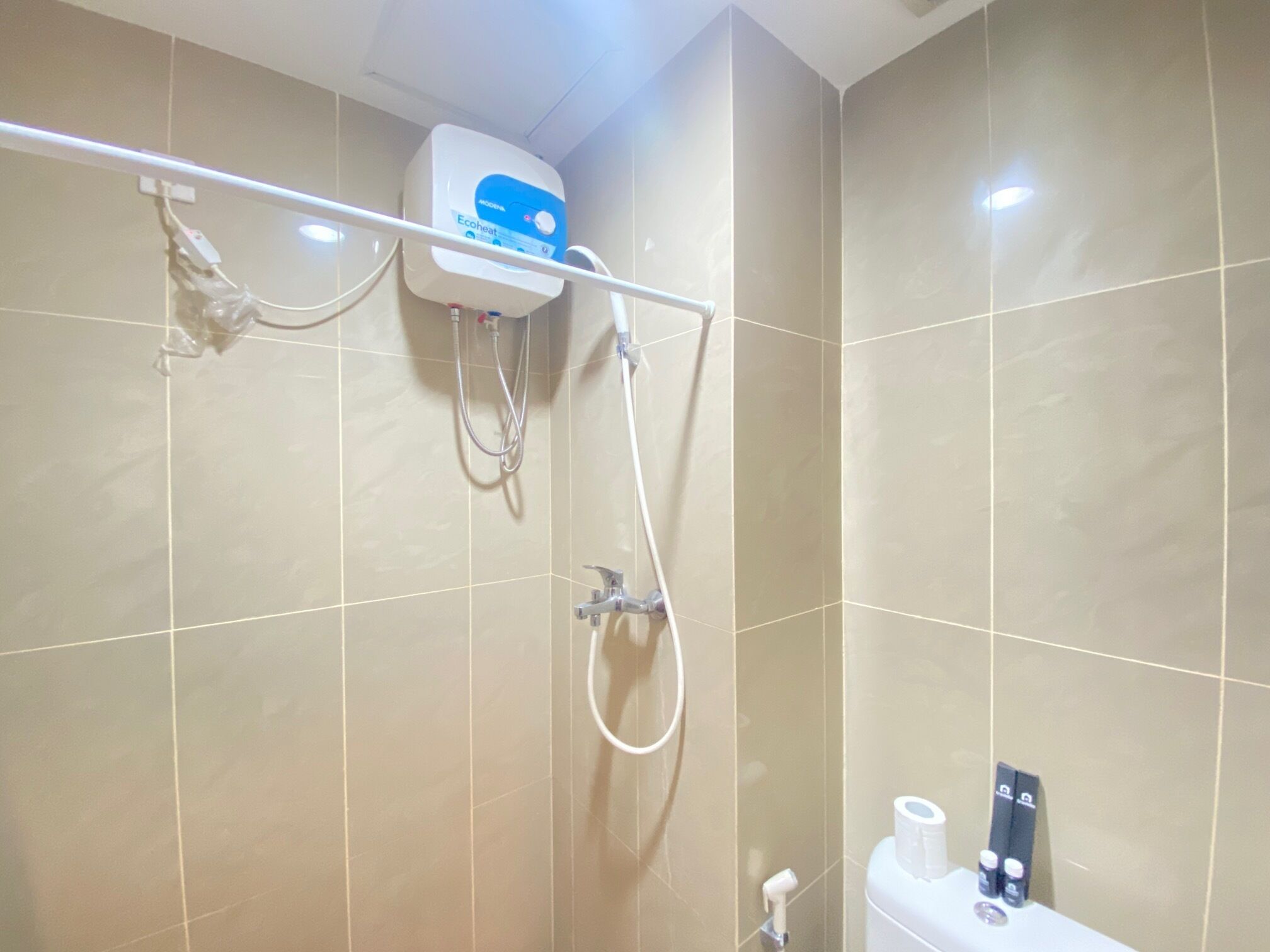 A bathroom with a shower, toilet, and a water heater mounted on the wall.
