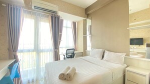 Habitación de hotel con una cama grande, un escritorio, una silla, un televisor y un aire acondicionado.