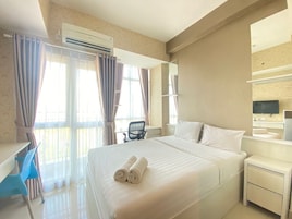 Habitación de hotel con una cama grande, un escritorio, una silla, un televisor y un aire acondicionado.