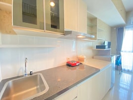 Una cocina moderna con un lavamanos de acero inoxidable, una placa de inducción roja y armarios blancos.