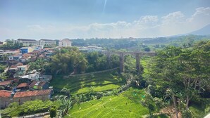Paisaje rural con campos en terrazas, un puente y edificios al fondo.