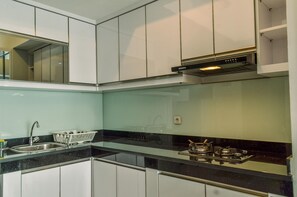 A modern kitchen with white cabinets, a black countertop, a stainless steel sink, and a gas stove.