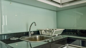 Uma cozinha moderna com uma pia de aço inoxidável, bancada preta e painel de parede verde.