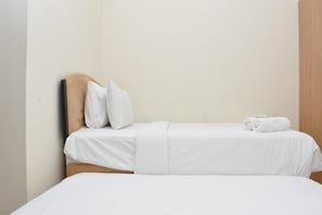 Ein Hotelzimmer mit zwei Betten, weißer Bettwäsche und einem hölzernen Kopfteil.
