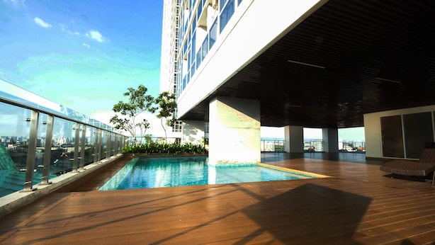 A rooftop pool area with a clear view of the city skyline, a wooden deck, and a covered seating area. - Stunning and Comfy Studio at Menteng Park Apartment (Jakarta)