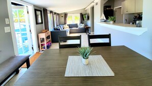 Un salon moderne comprenant un canapé, une table à manger avec des chaises et un coin cuisine avec des placards et un plan de travail.