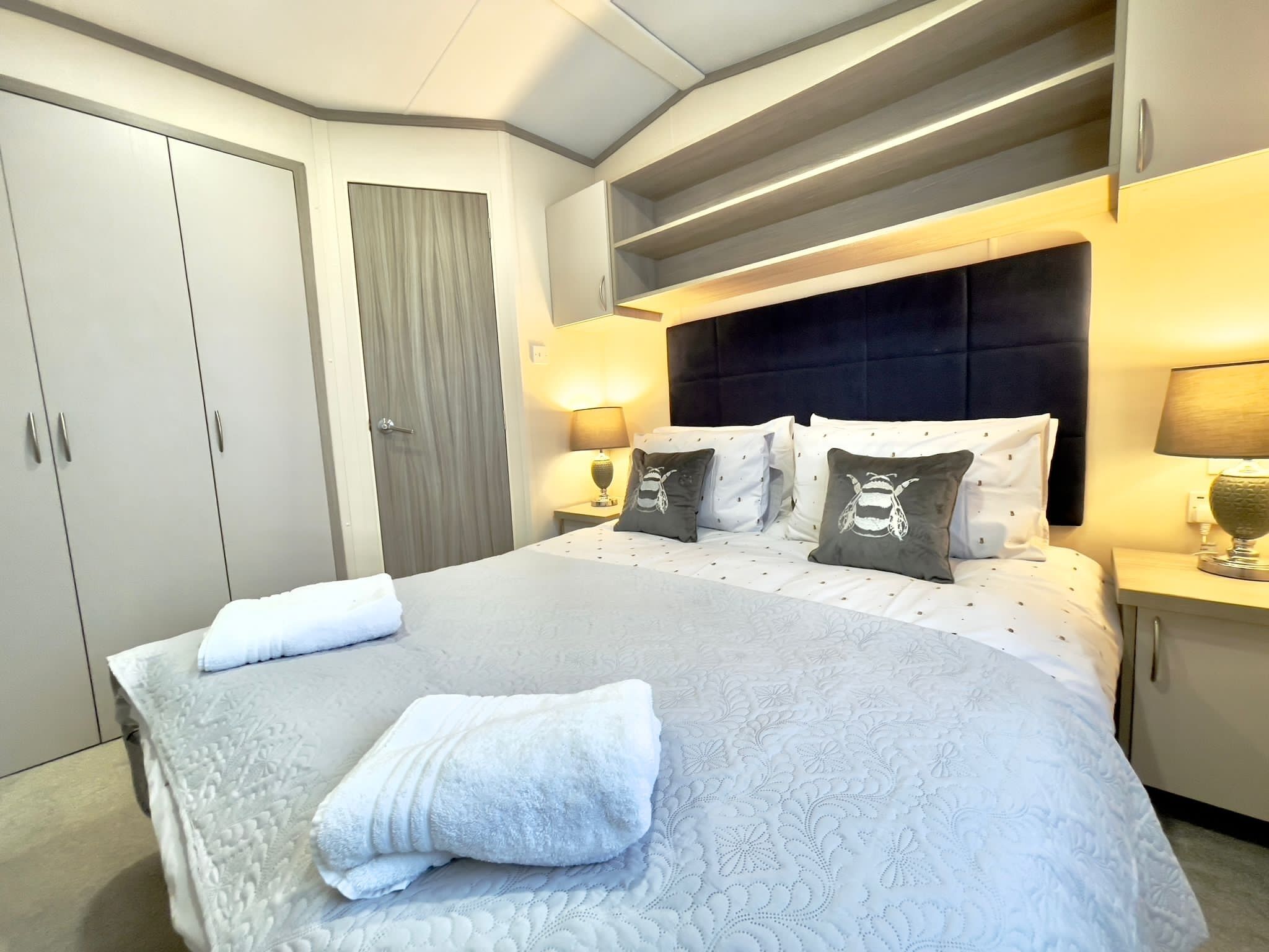 Ein Hotelzimmer mit einem großen Bett, zwei Nachttischen mit Lampen, einem Kleiderschrank und einer Tür mit Vorhang.
