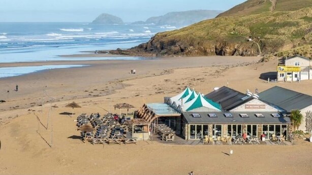 A beachside building with a green roof and a sign that reads "The Natural House." - 63 Bude Perran Paradise (Newquay)