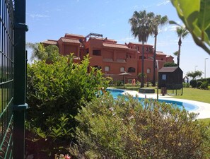 A hotel with a swimming pool surrounded by lush greenery and palm trees. - Spacious flat, very quiet and with gardens (Buenas Noches)