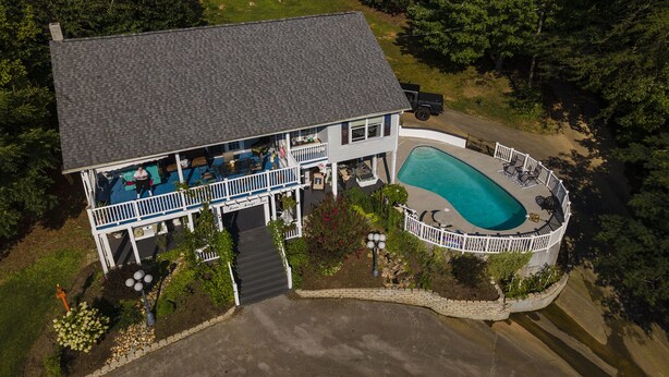 Une maison à deux étages avec une piscine, un patio couvert et une allée.