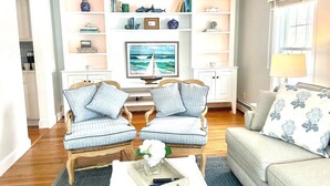 Ein Wohnzimmer mit Fernseher, zwei Sesseln, einer Couch und einem Couchtisch.