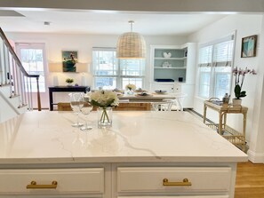 A spacious kitchen with a large island, white cabinetry, and a view of the city through large windows.