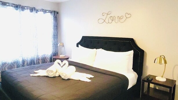 A bedroom with a large bed, a bedside table with a lamp, and a wall with the word "Love" written on it. - Best Apartment in Kissimmee ! 1 Free dinner ! (Kissimmee)