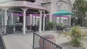 A covered outdoor seating area with tables and chairs, a small stage, and a green umbrella. - Best Apartment in Kissimmee ! 1 Free dinner ! (Kissimmee)