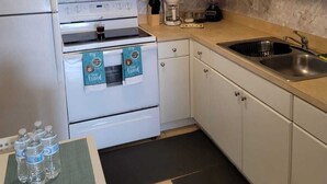 Eine kleine Küche mit weißen Schränken, einem Einbauofen, einer Spüle und einer Kaffeemaschine.