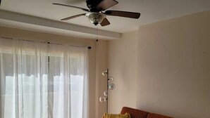 Ein Wohnzimmer mit einer Couch, einem Hocker und einem Deckenventilator.