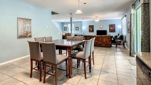 Un salón amplio con una mesa de comedor, sillas, un sofá y un televisor.