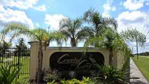 Un letrero para Crystal Cove Resort con un jardín ajardinado al frente.