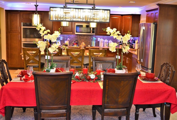 A dining area with a red tablecloth, wooden chairs, and a chandelier.
