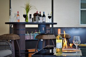 Un espace bar doté d’un assortiment de bouteilles, de verres et d’un foyer.
