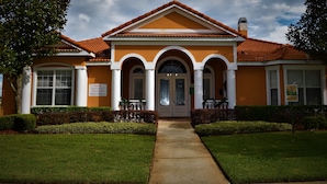 A two-story building with a symmetrical facade, featuring a central entrance with a double door, flanked by two columns and a triangular pediment. - Exquisite Destination Villas... Crystal location (Kissimmee)