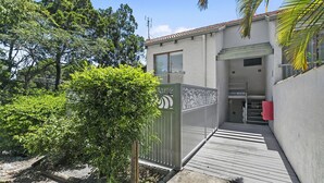 A residential building with a gated entrance, a wooden deck, and a small garden area.