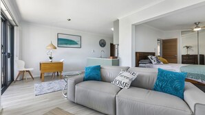 A modern bedroom with a sofa, a desk, a bed, and a bathroom visible through an open door.