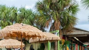Un bar tiki con sombrillas de paja, taburetes de madera y un paseo adoquinado de ladrillo.