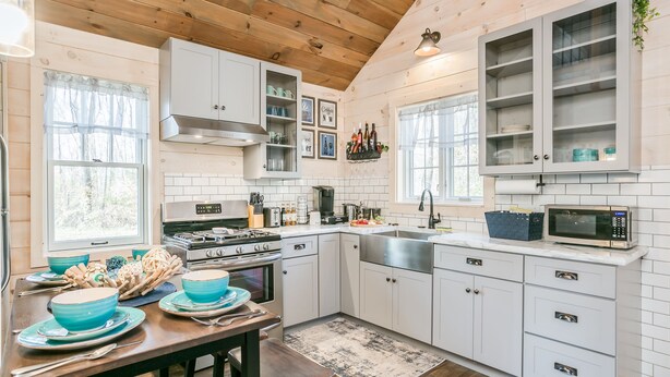 A modern kitchen with white cabinets, a stove, and a microwave.