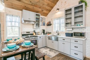 Una cocina moderna con armarios blancos, estufa y microondas.