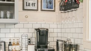 A kitchen with white cabinets, a coffee maker, wine glasses, and a wine rack.