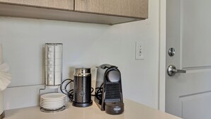 Un comptoir de cuisine avec une machine à café, une bouilloire et une pile d’assiettes.