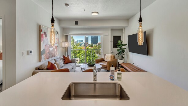 Un salon moderne avec un îlot central, un canapé, une table basse et une vue sur la ville.