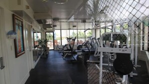 A gym with exercise equipment, large windows, and a view of the outdoors. - Beautiful Studio at Luana Waikiki Near Beach  (Honolulu)