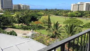 A view of a hotel with a rooftop terrace, lush greenery, and a clear view of the ocean. - Beautiful Studio at Luana Waikiki Near Beach  (Honolulu)