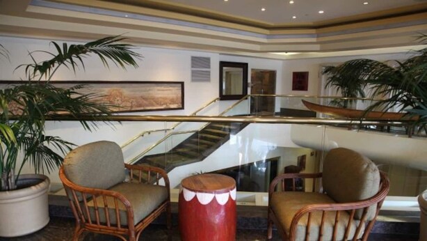 A lobby with wicker chairs, a red drum, and a staircase. - Beautiful Studio at Luana Waikiki Near Beach  (Honolulu)