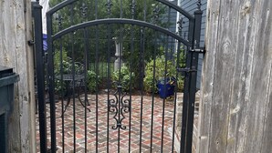 Ein verschlossenes Tor mit einem Ziegelweg, der zu einem Garten führt.
