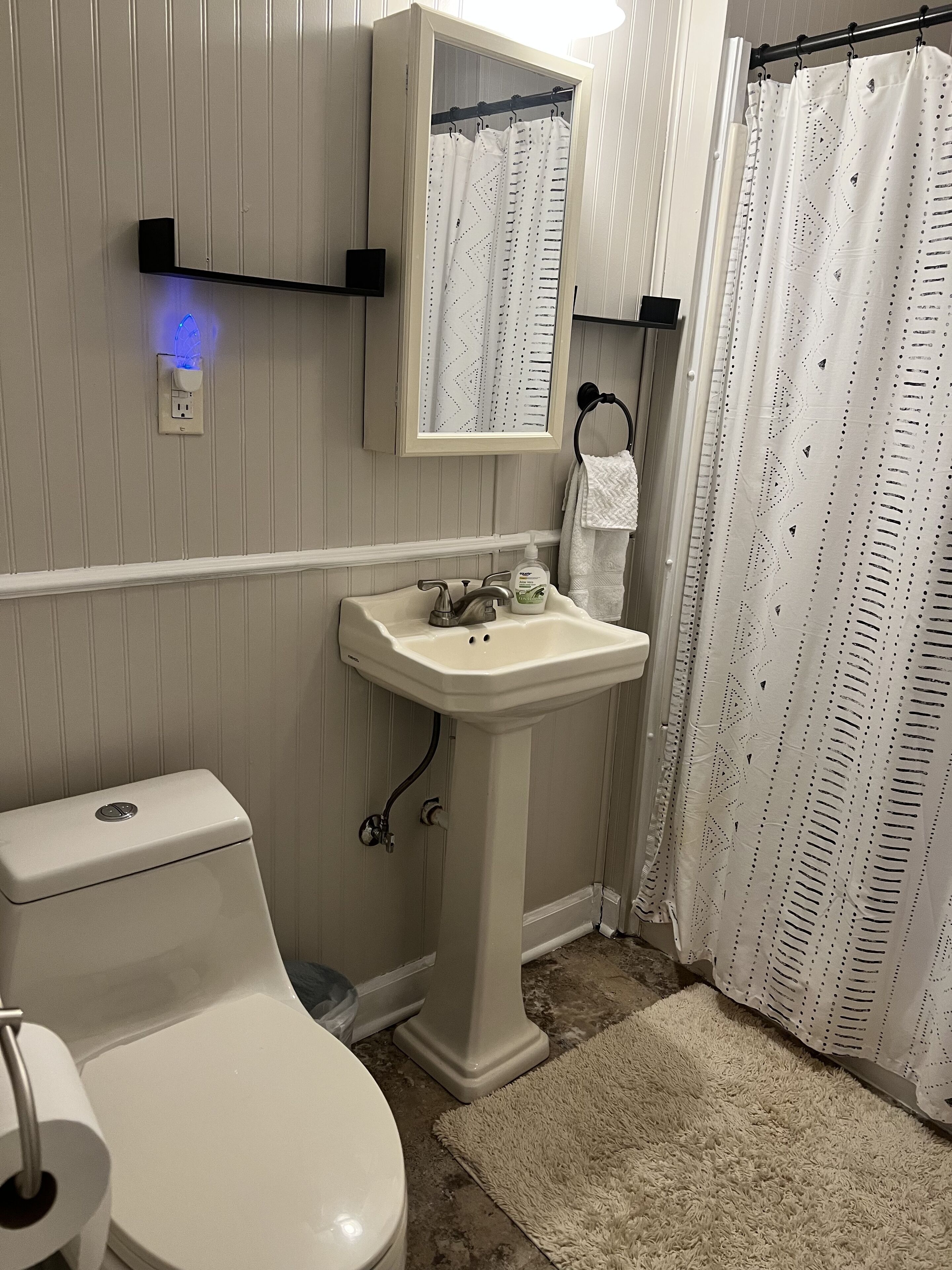 Un baño con inodoro, lavamanos, espejo y cortina de ducha.