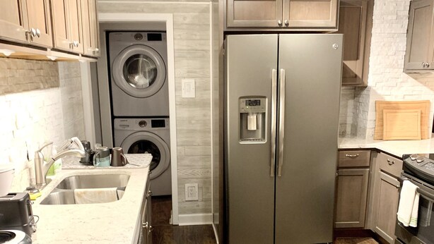 A modern kitchen with stainless steel appliances, a built-in washer and dryer, and a patterned rug.