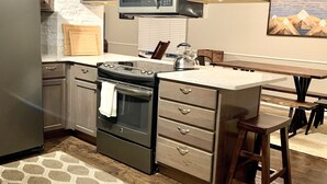 A modern kitchen with dark wood cabinets, a stainless steel refrigerator, a microwave, and an oven.