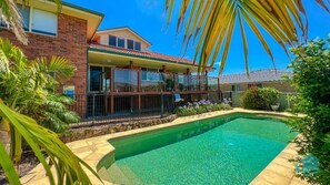 A residential property with a swimming pool, a covered patio, and a brick facade.