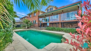 Ein Schwimmbecken, umgeben von einem Ziegelhaus mit einem Balkon.